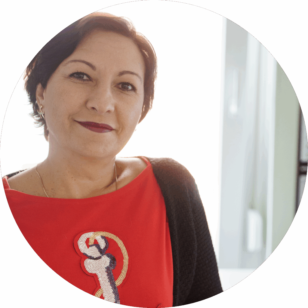 Frau mit dunklen kurzen Haaren und rotem Oberteil blickt freundlich in die Kamera