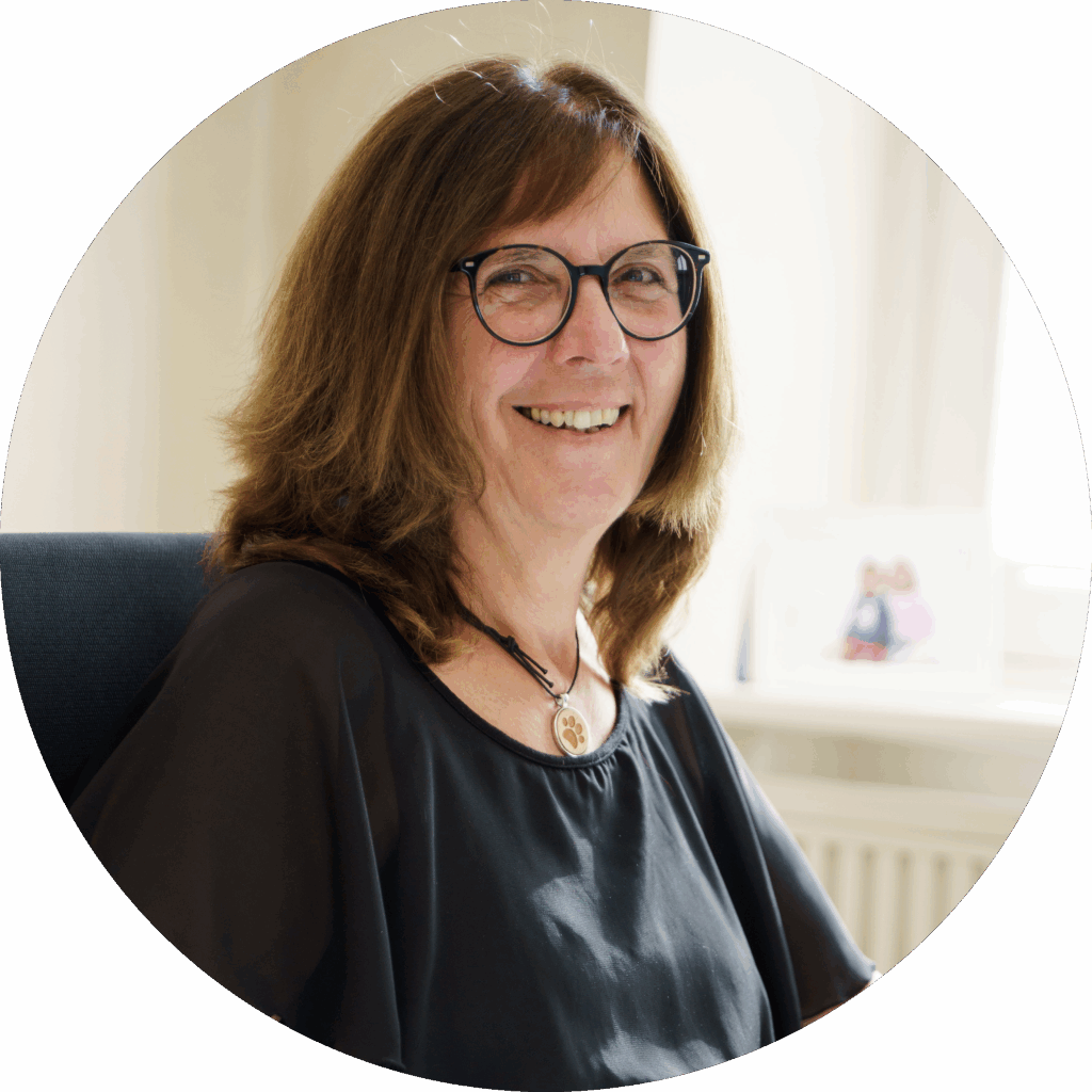 Aeltere Frau mit Brille laechelt in die Kamera